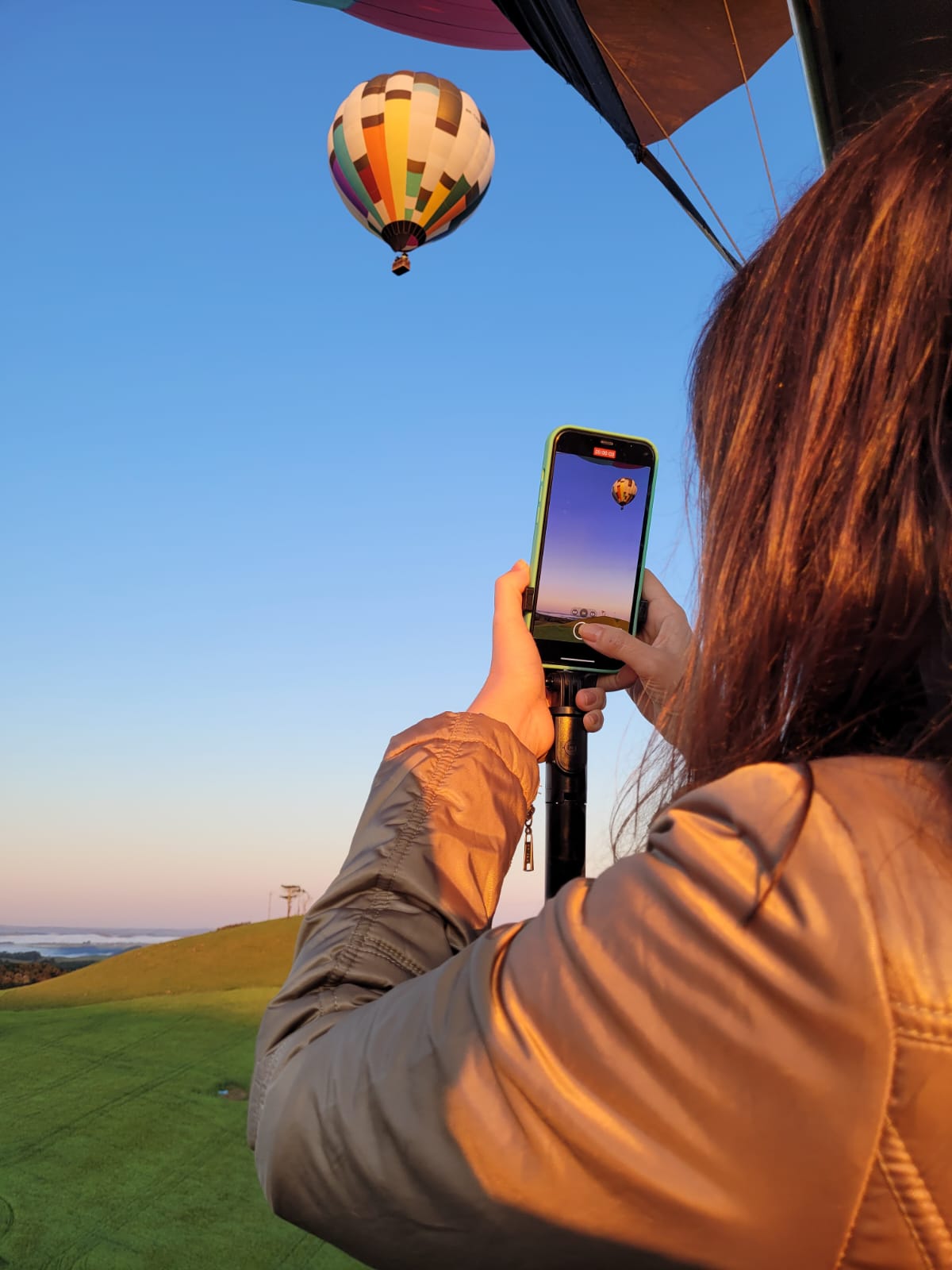 Passageira fotografando outro balão em voo com céu azul limpo ao fundo
