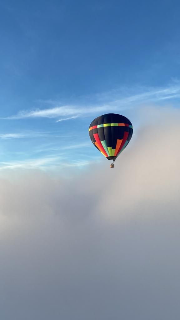 Balão da Cambará Balonismo em voo sobre nuvens baixas com céu azul vibrante